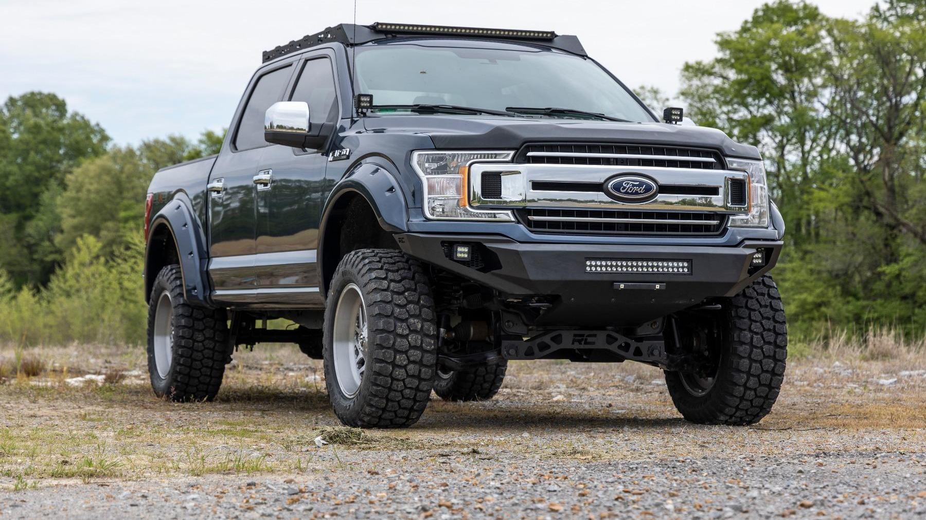 A lifted Ford F-150 with a Rough Country bumper and light bar